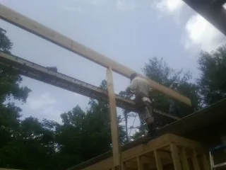 Carpenter setting a ridge beam over a new addition frame — Ice Dam Removal by Roofing Brothers in Bossier City