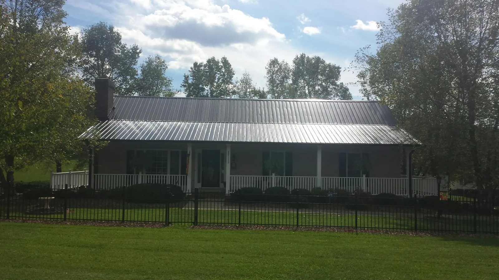 Gray metal roof on a brick ranch with a full width front porch — Gutter Guard Installation work by our crew in Bossier City