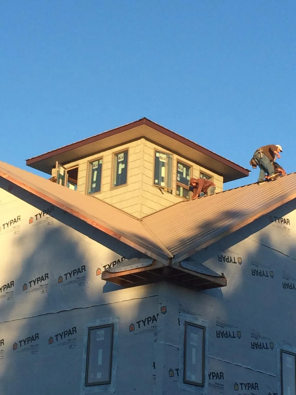 Roofers working around a rooftop cupola on a new metal roof at sunset — Roof Waterproofing in Bossier City by Roofing Brothers